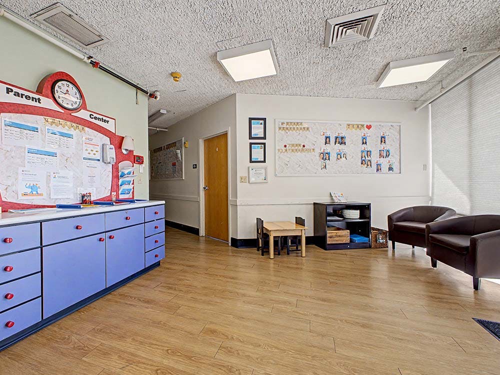 Parent information board, chairs, small table, and cabinets in a waiting area