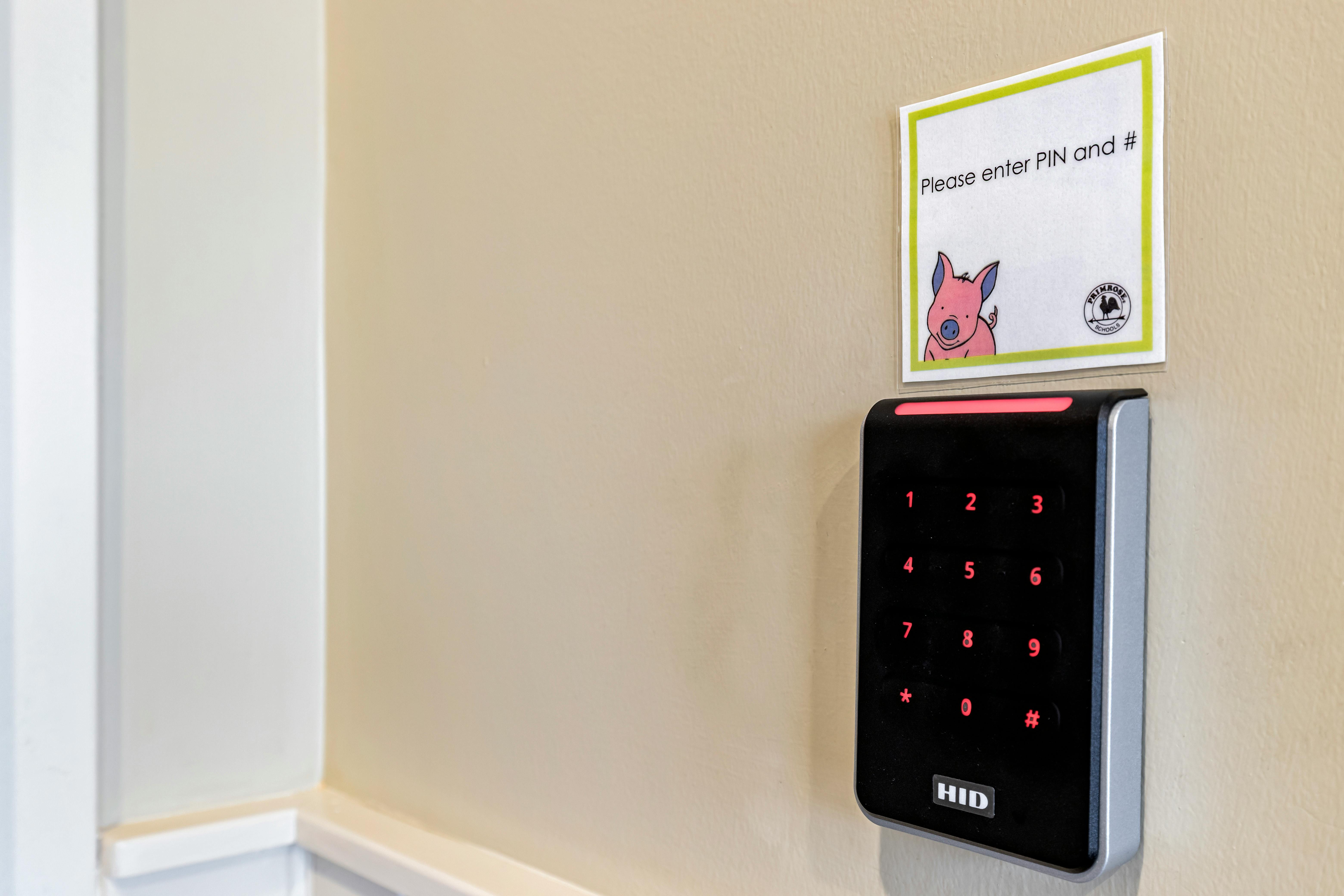 A black keypad access system on a wall with a sign that reads "Please enter PIN and #"