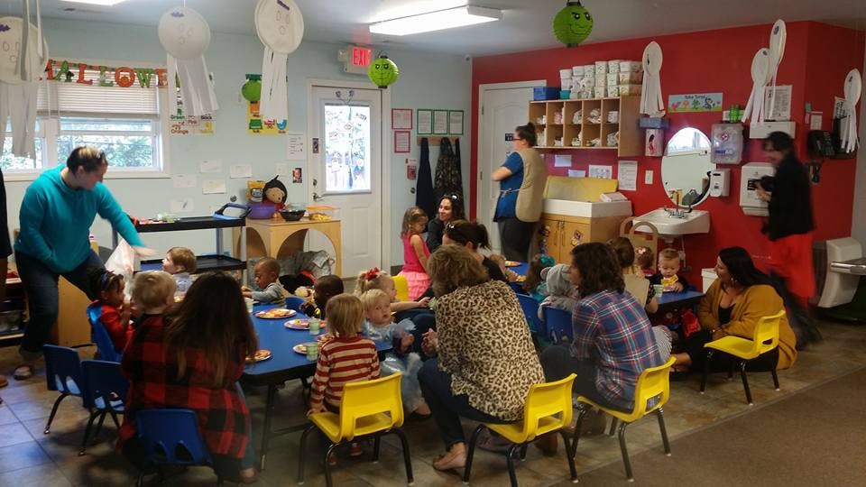 Adults and children gathered around tables in a room