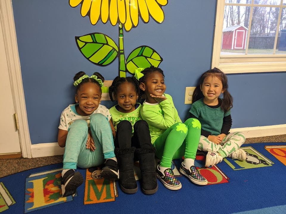 Four children sitting on a rug in a classroom