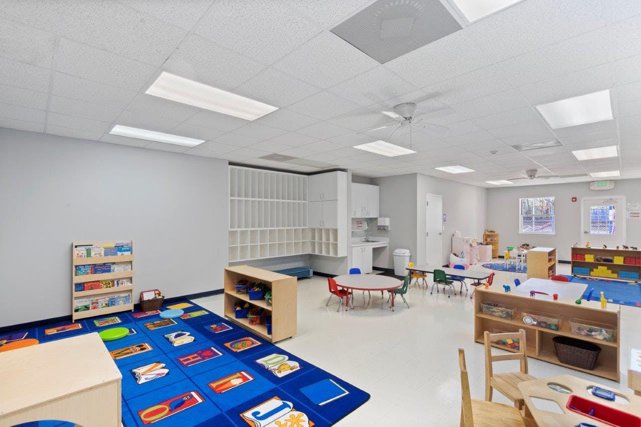 Empty classroom with small tables, chairs, and shelves