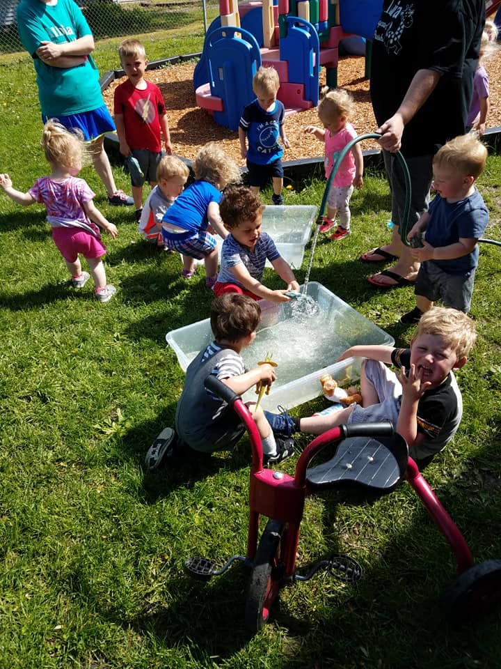 Children playing with water in plastic bins outdoors
