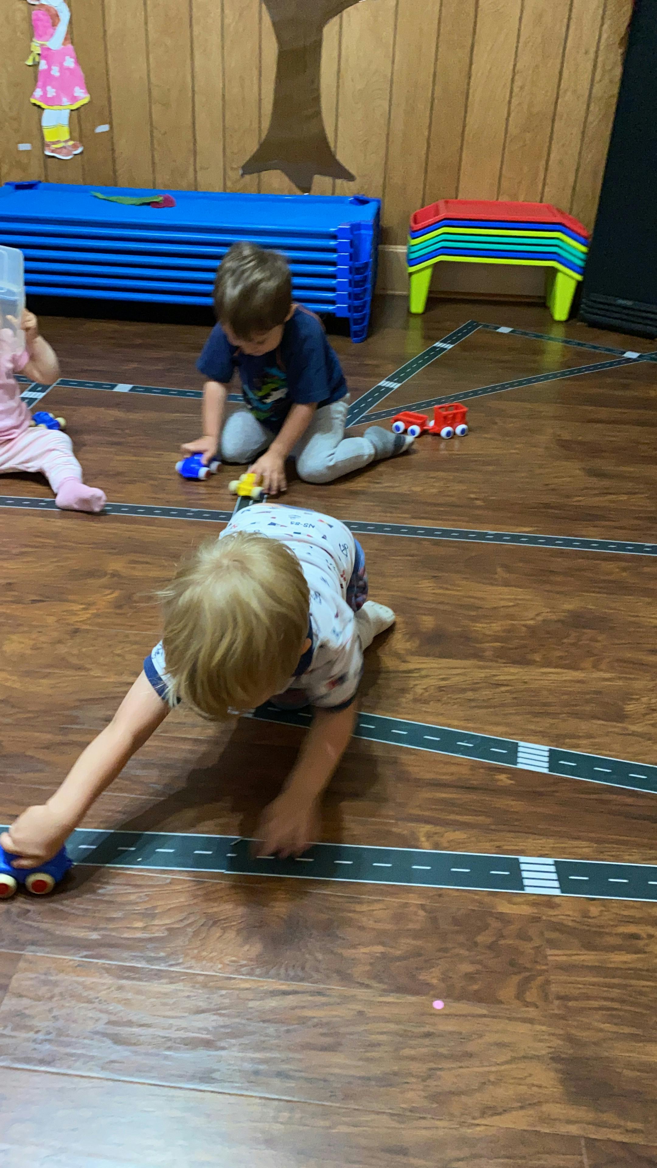 Children playing with toy cars on a road mat