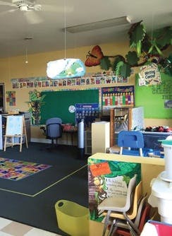 Empty classroom with a green chalkboard and colorful decorations