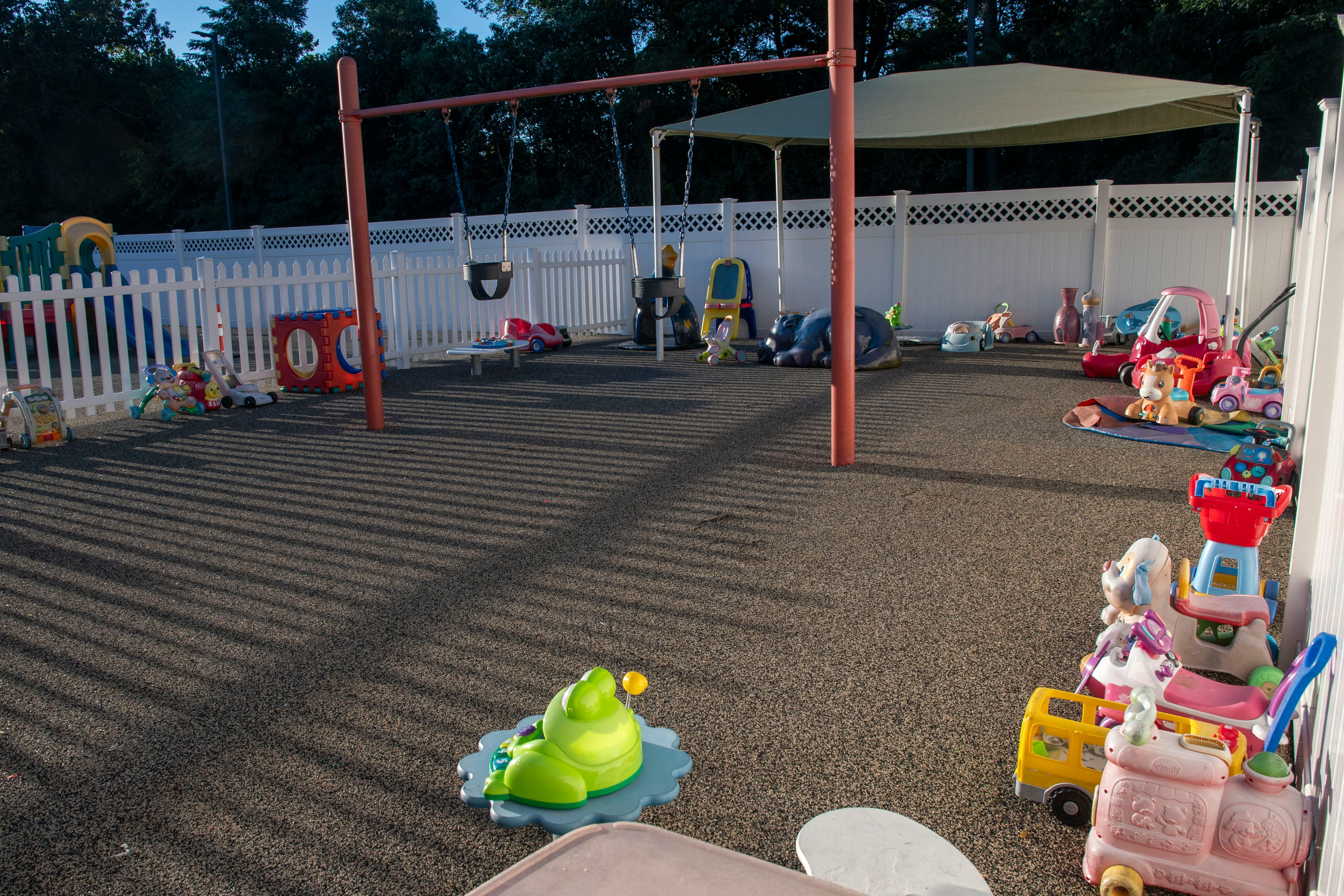 Outdoor playground with swings, shade structure, and various toys