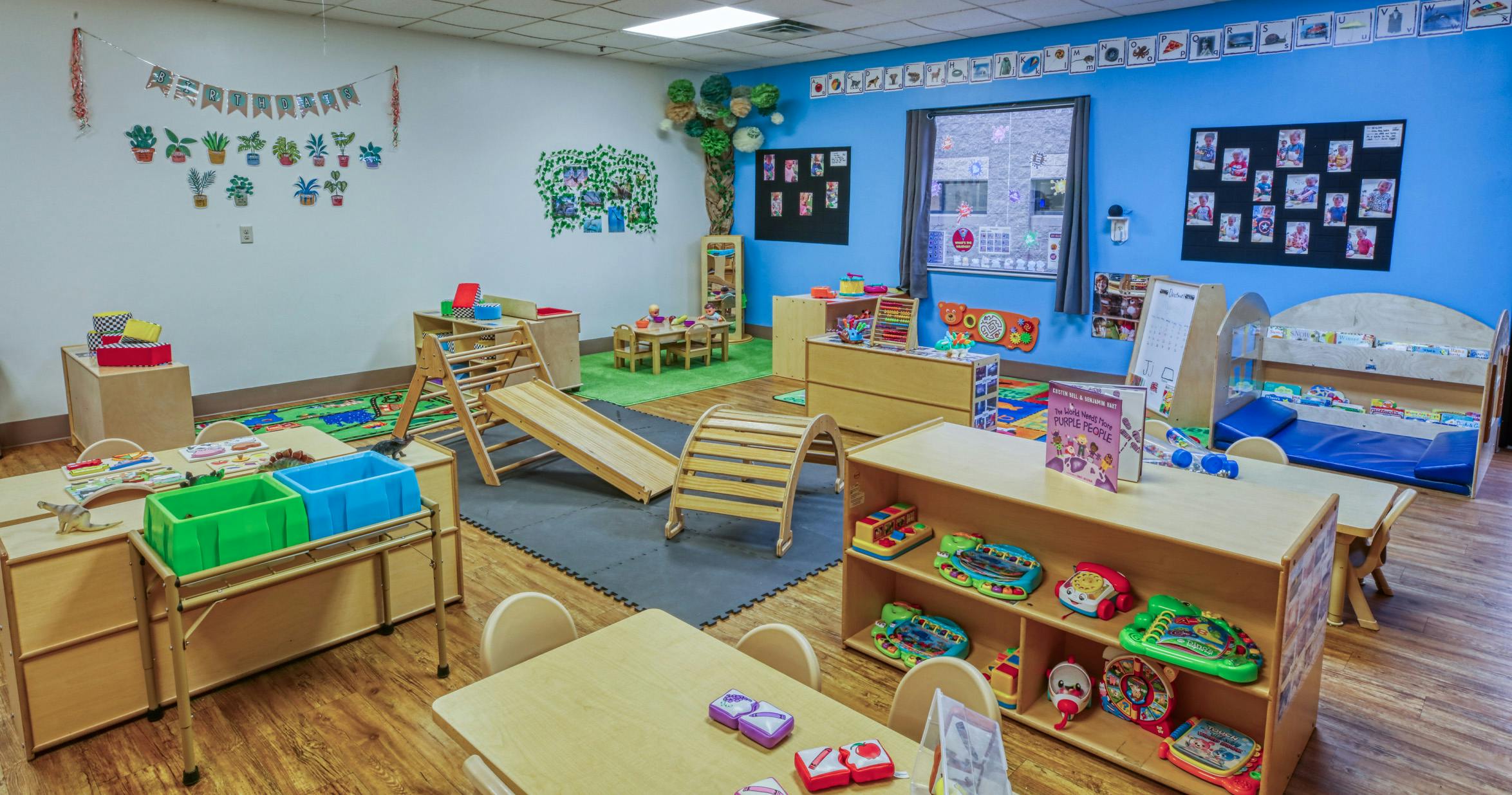 A classroom with small tables and chairs, play mats, and toys