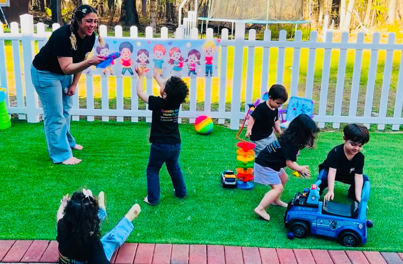 Adult person blowing bubbles for four children in an outdoor play area