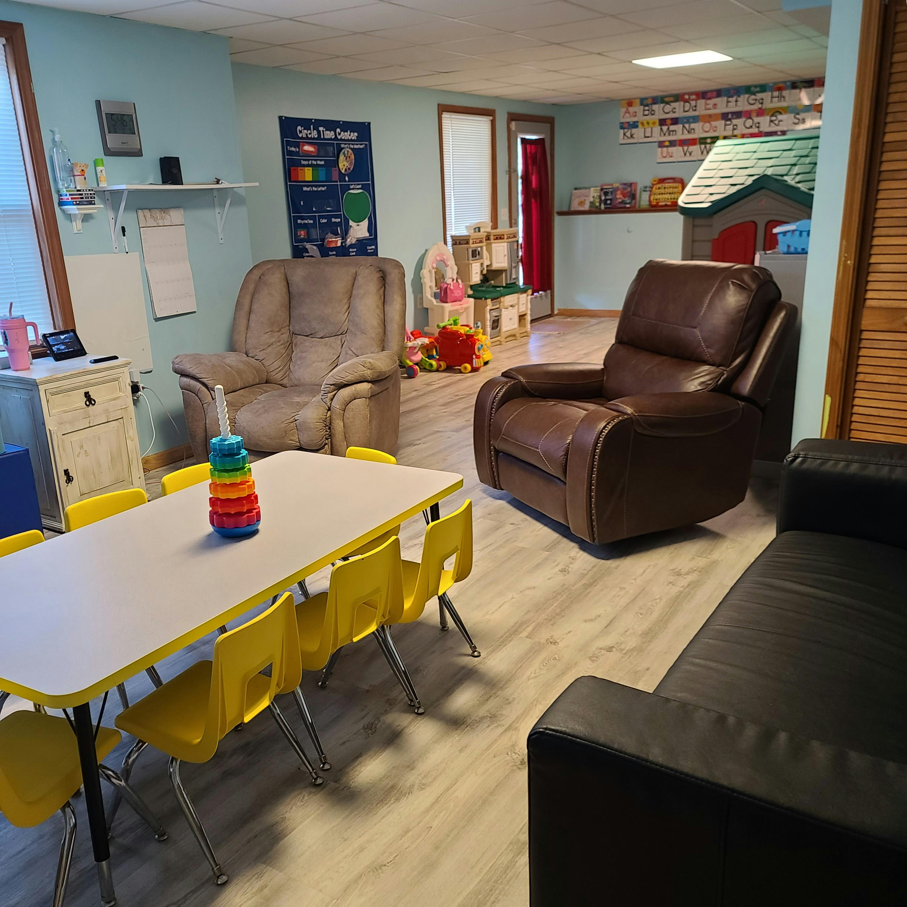 Playroom with child-sized table and chairs, recliners, and toys