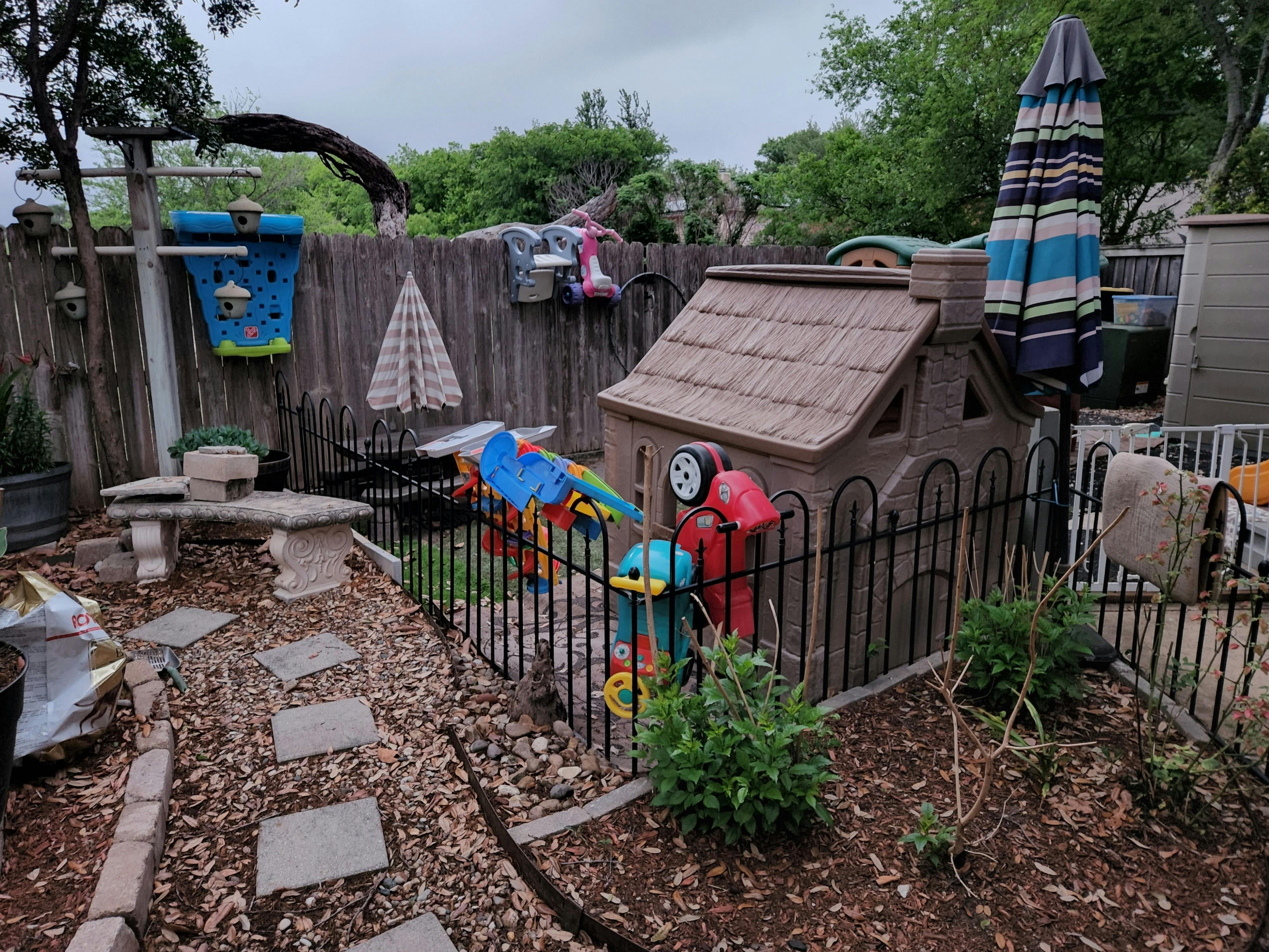 Backyard play area with a plastic playhouse and toys