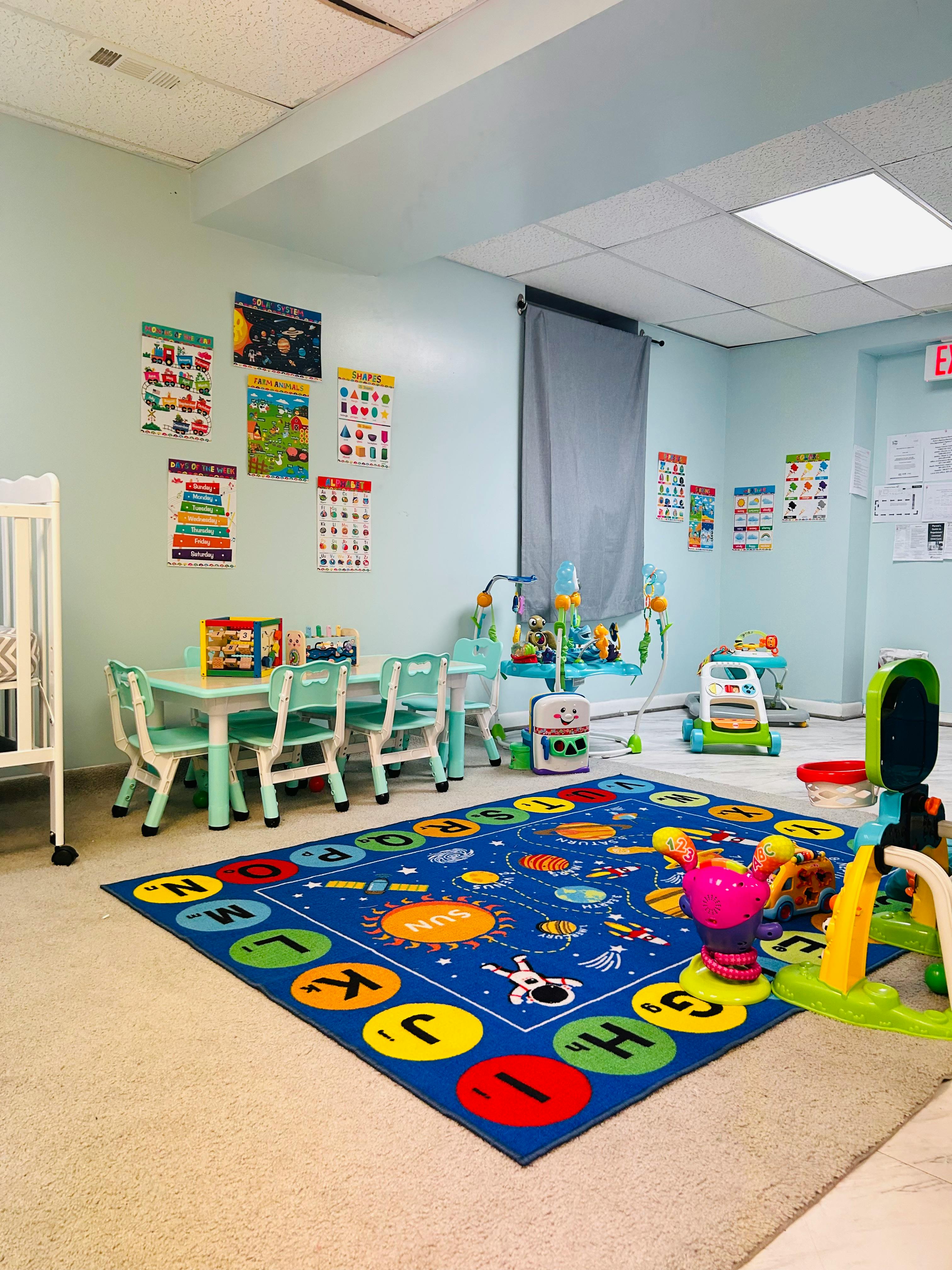 Childcare room with learning charts, a table with chairs, and toys on a rug