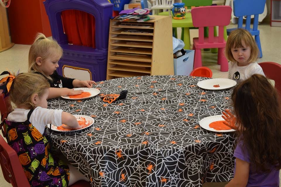 Children sitting at a table with a spiderweb tablecloth