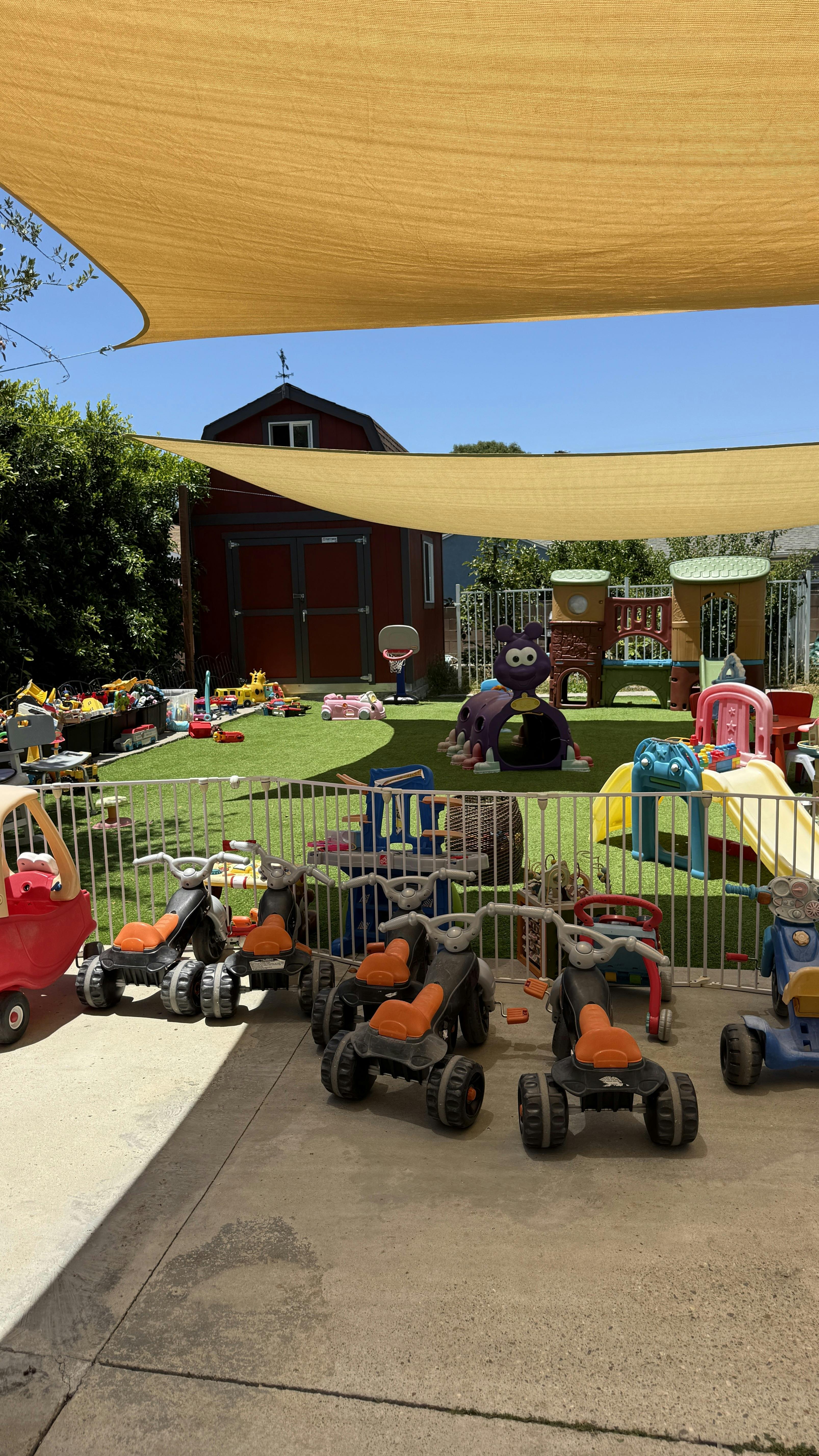 Childrens playground with play vehicles and equipment under a sun shade