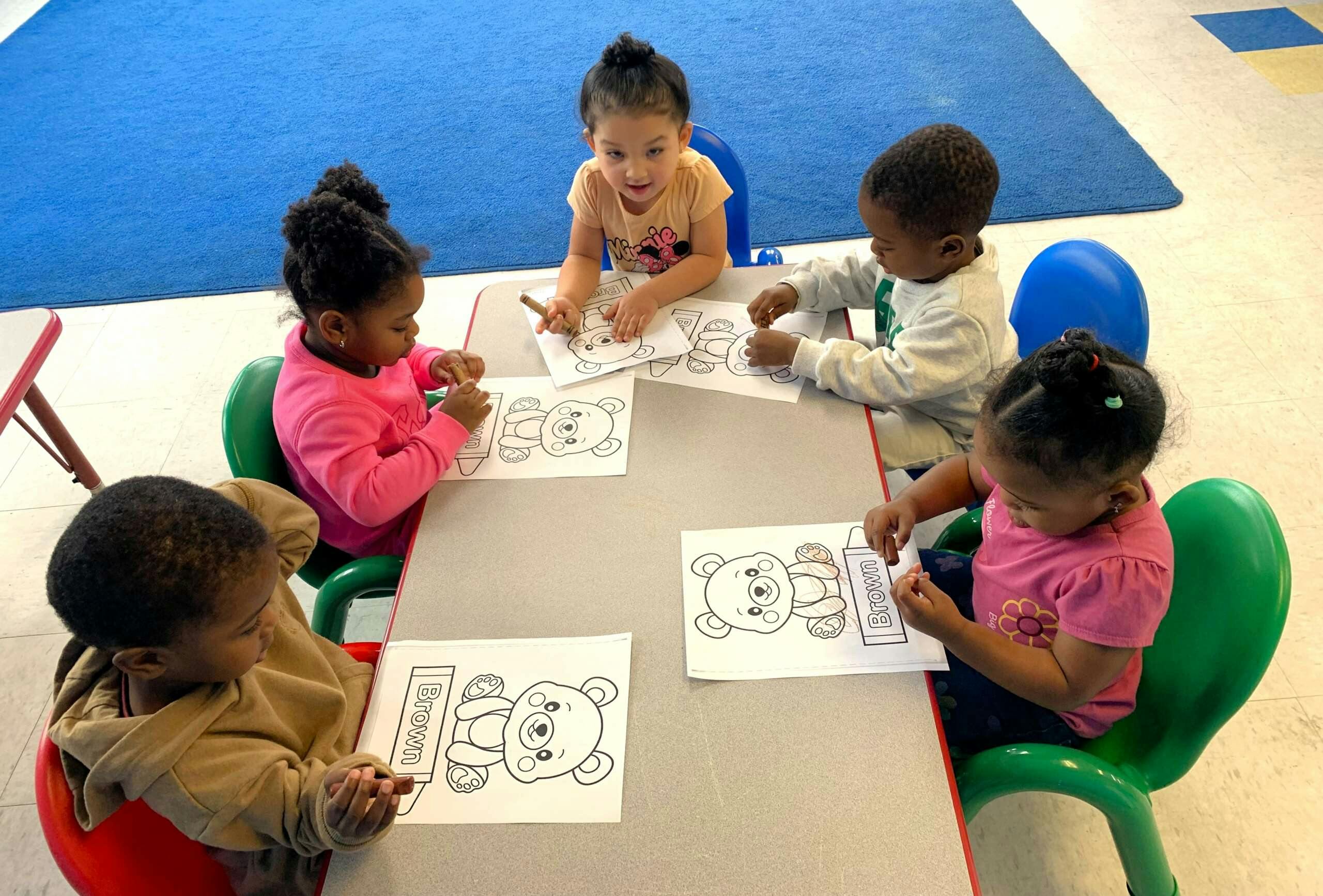 Five children coloring pictures of bears at a table