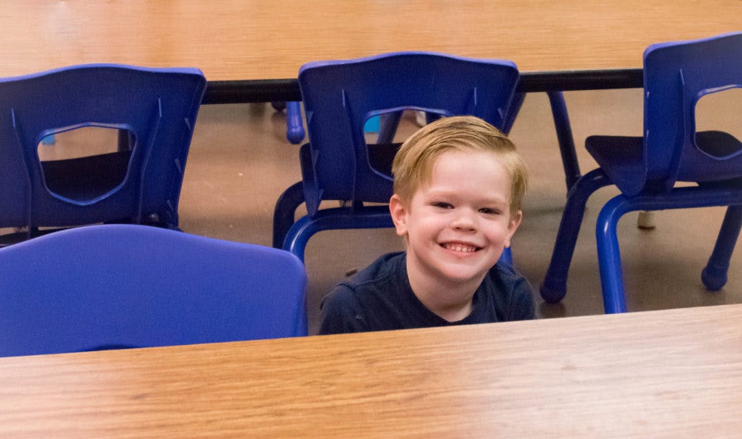 Child smiling behind a table