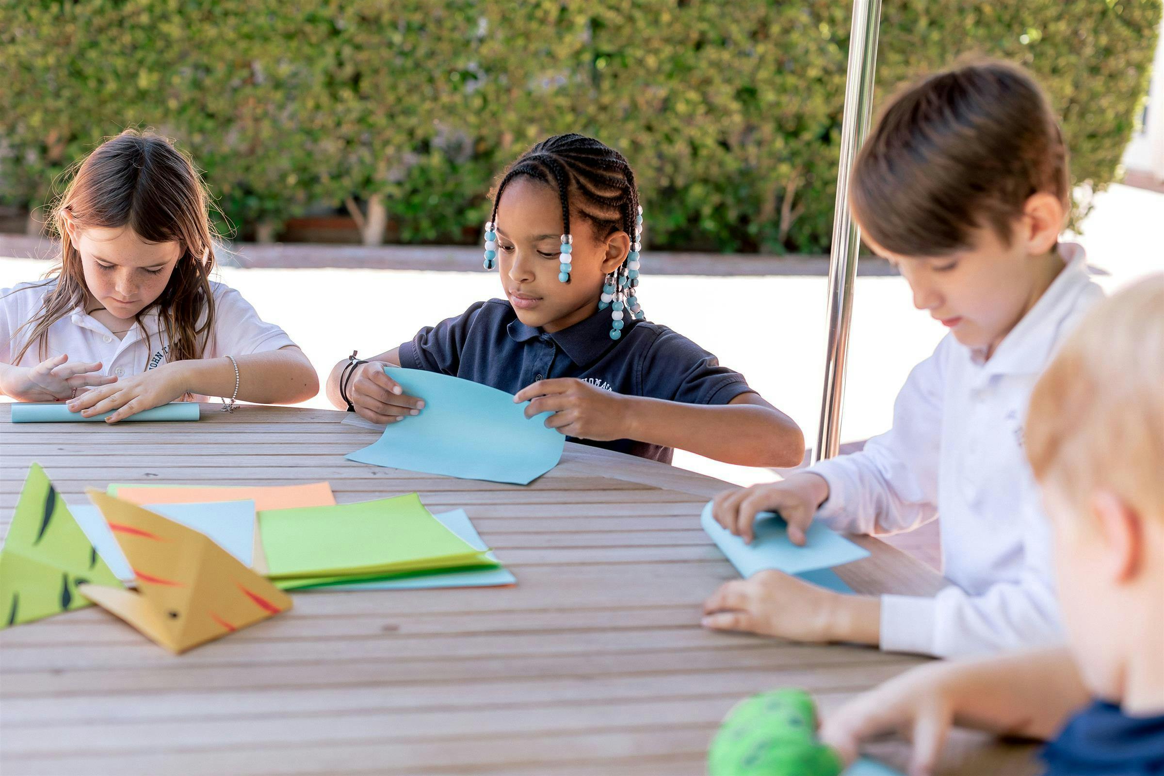 children sitting at a table doing crafts with paper crafts