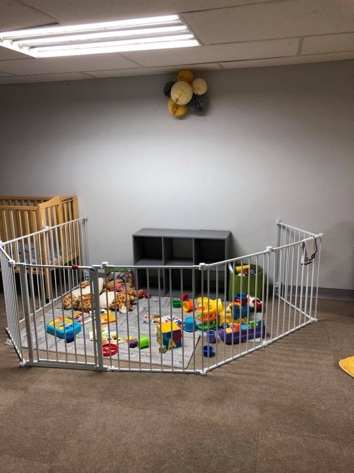 Playpen with toys and a crib in a room