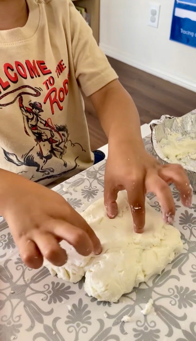 Child's hands pressing into a white dough-like substance