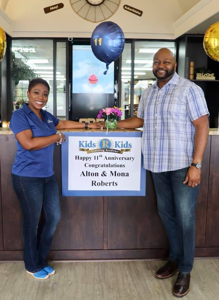 Two people standing next to a sign that reads "Happy 11th Anniversary"