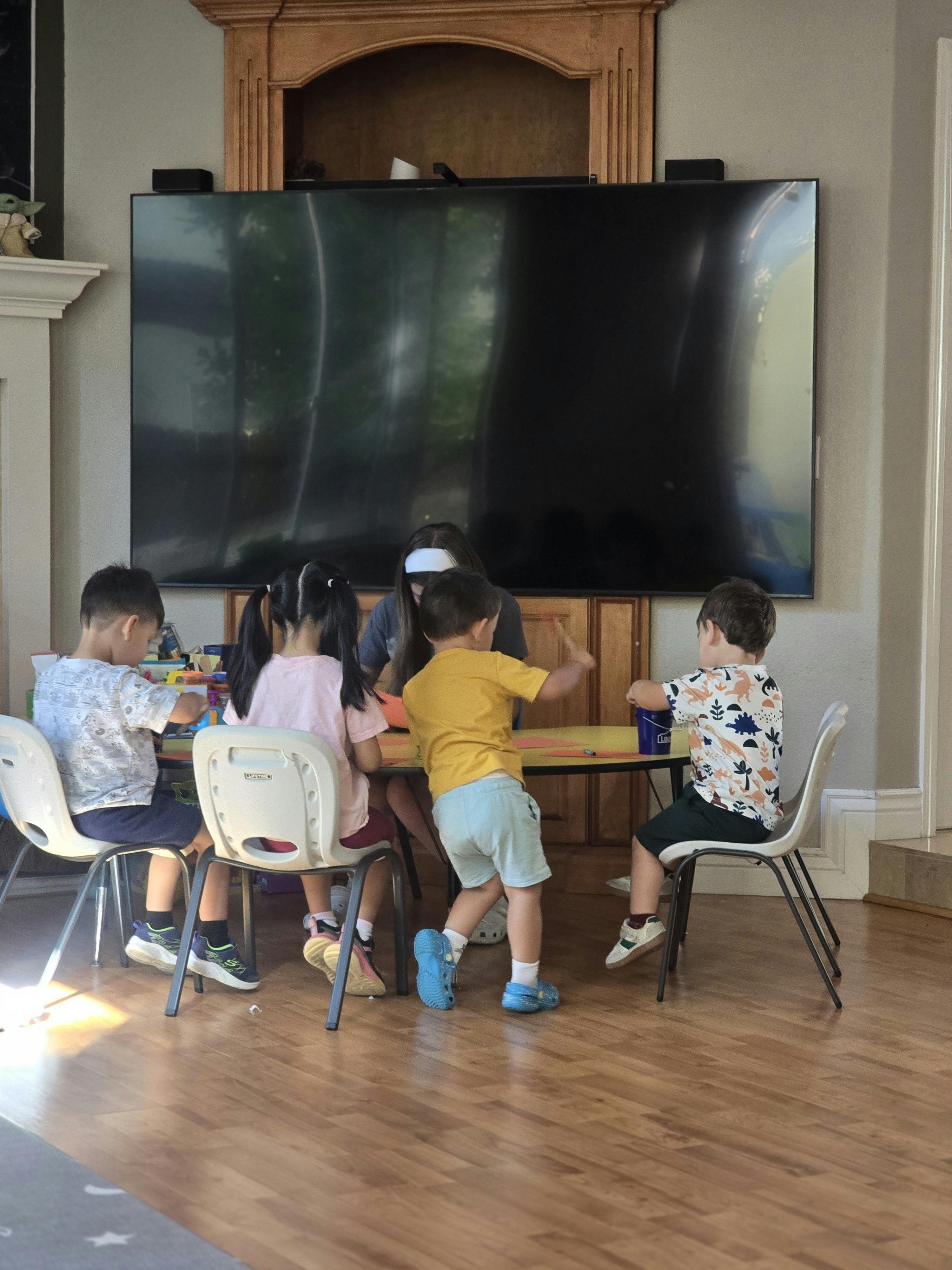 Group of children and a person sitting at a table engaged in a craft activity