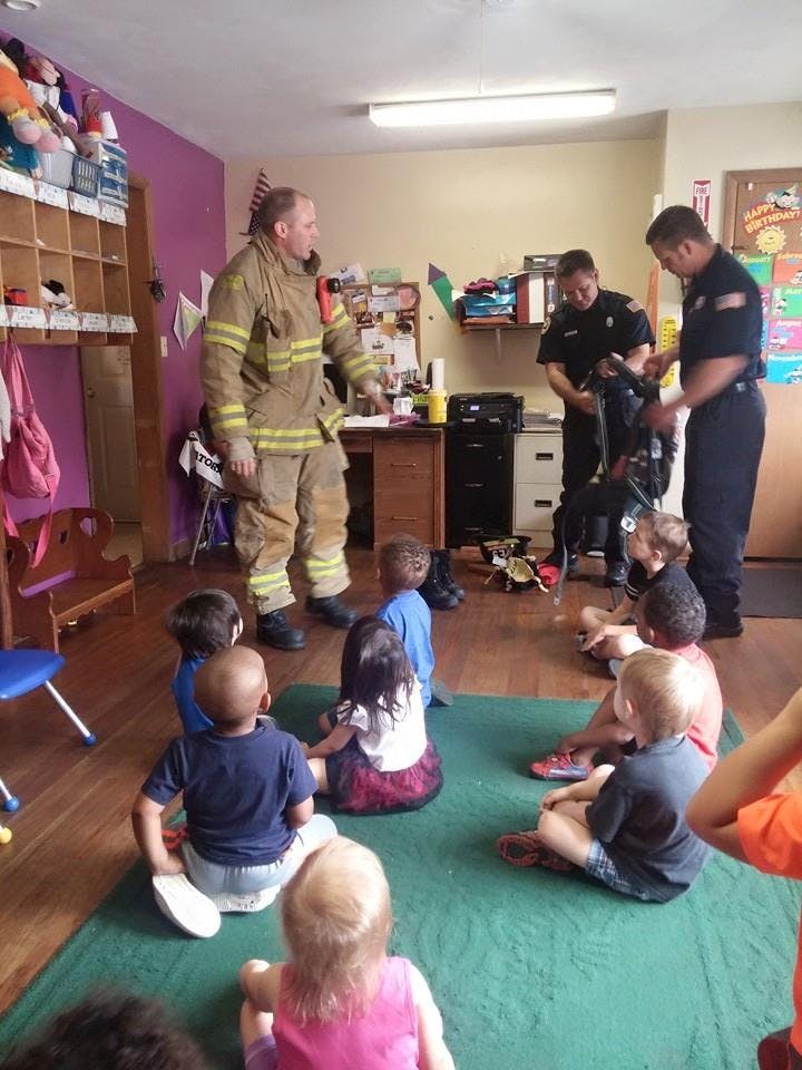 Firefighters demonstrating equipment to children in a classroom