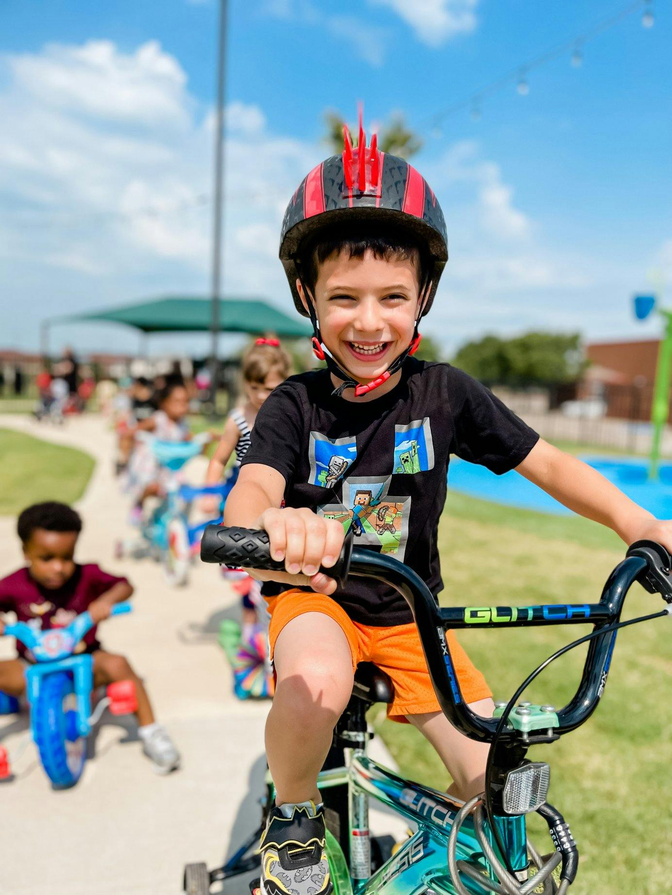 Child wearing a helmet riding a bicycle on a path with other children
