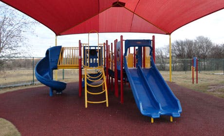 Playground with slides and climbing structures under a red canopy