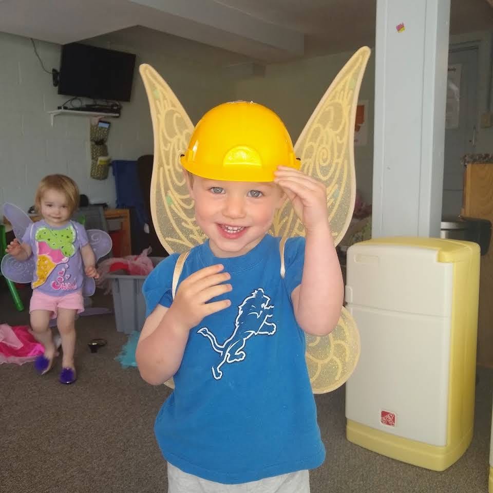 Child wearing a yellow hard hat and fairy wings