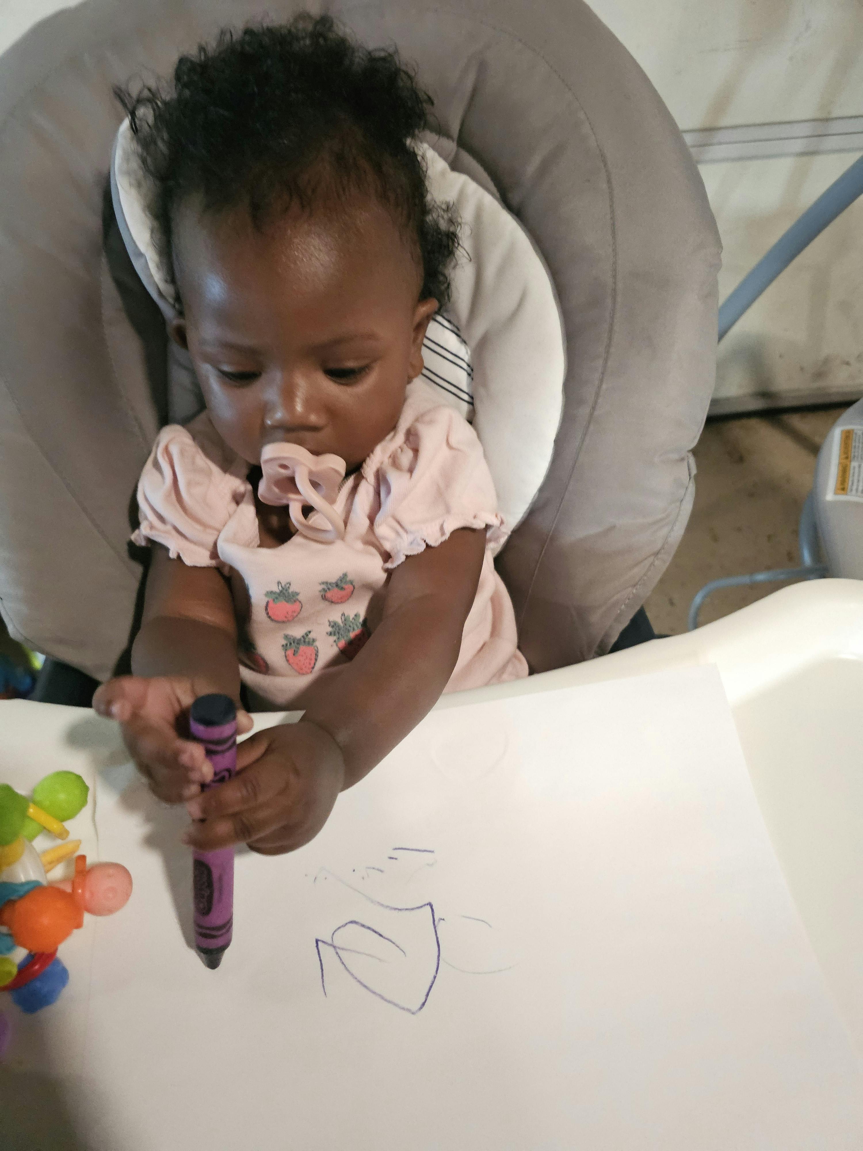 Child drawing on paper with a purple marker