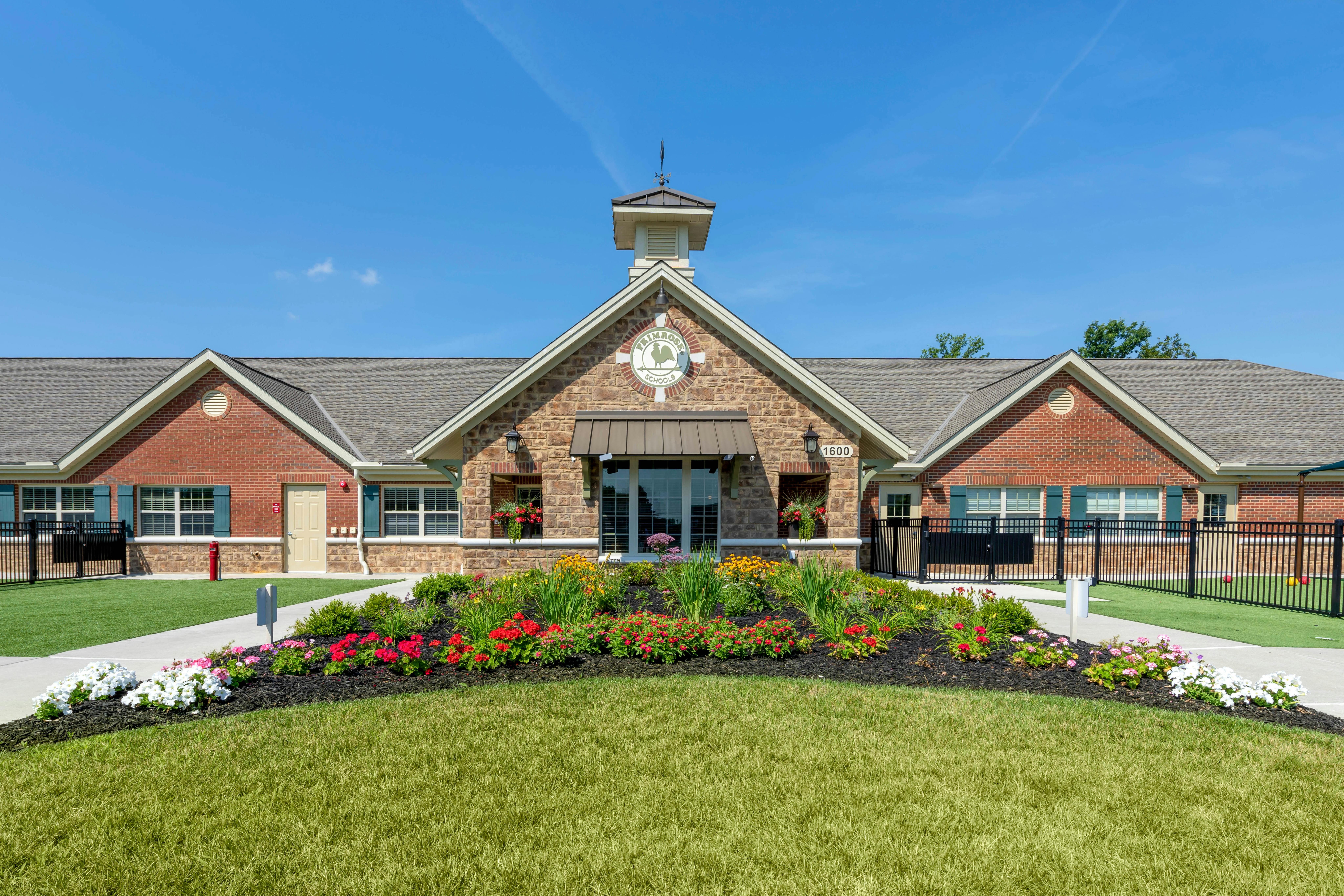 Building exterior with brick and stone, a flower bed, and a green lawn