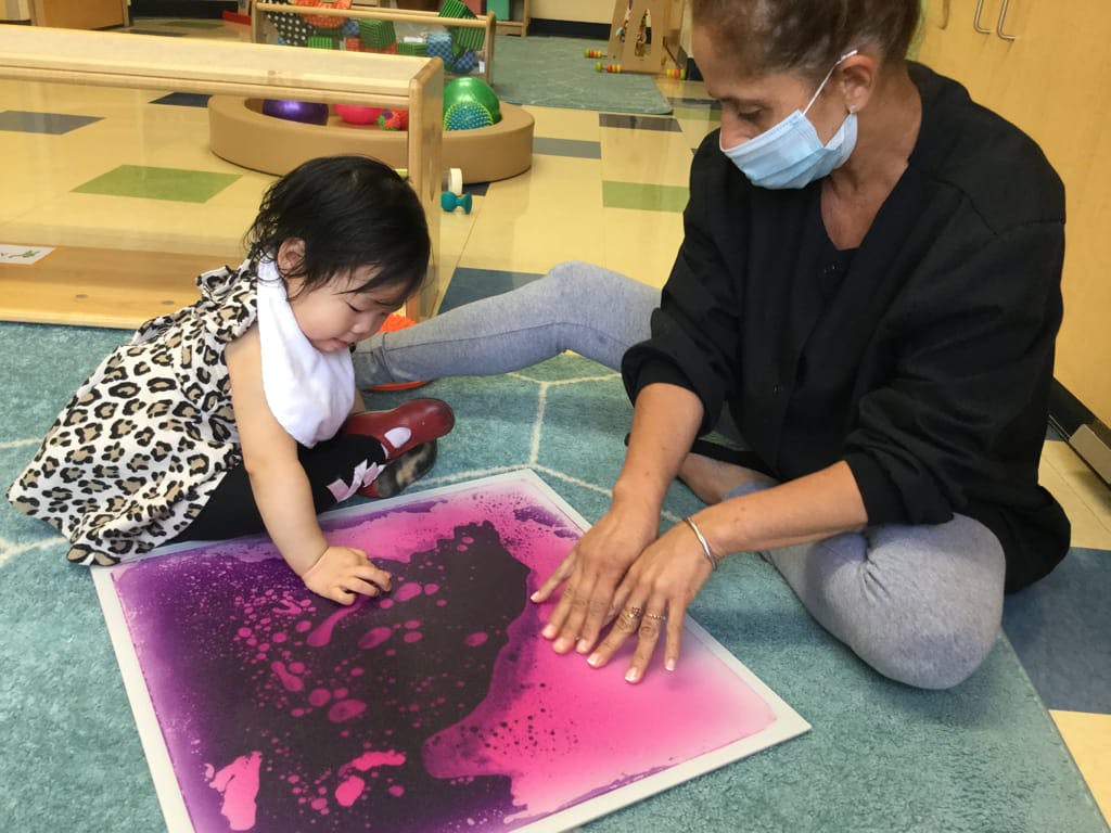 Adult and child playing with a sensory mat on the floor