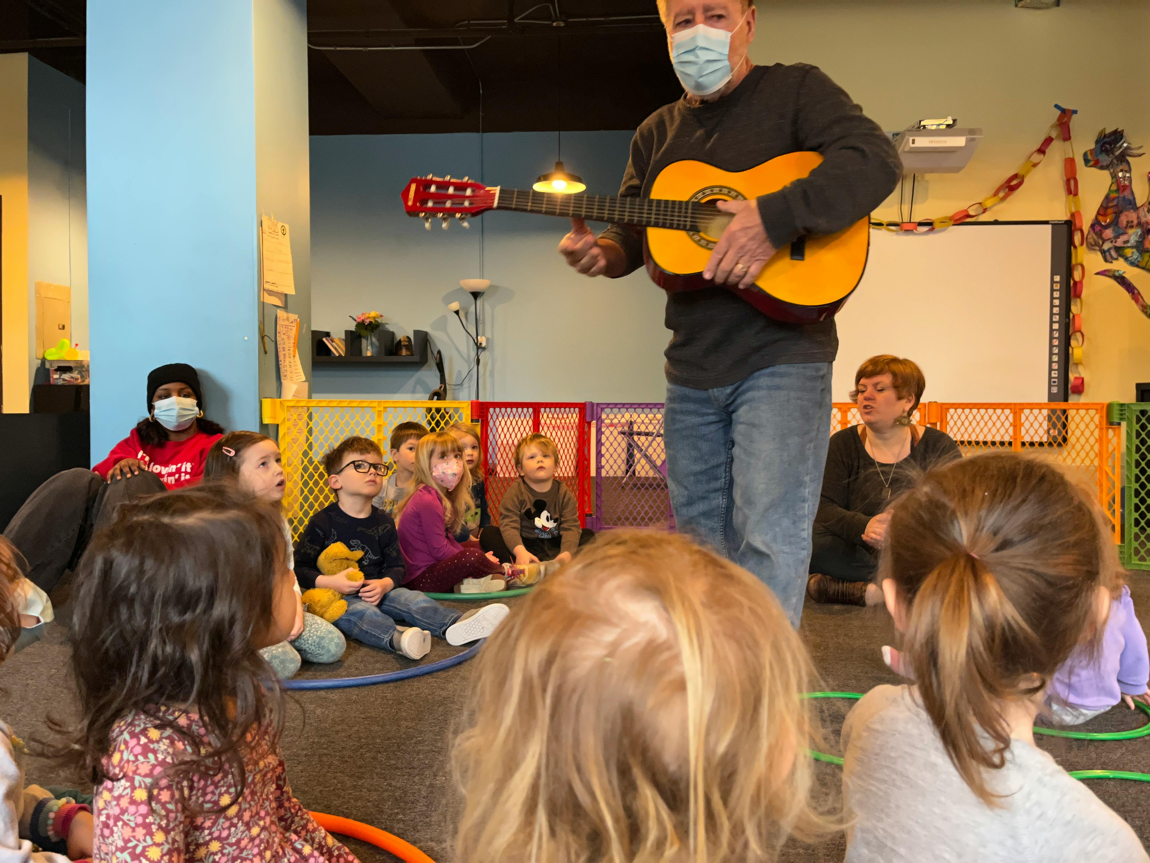 Person playing guitar for a group of children