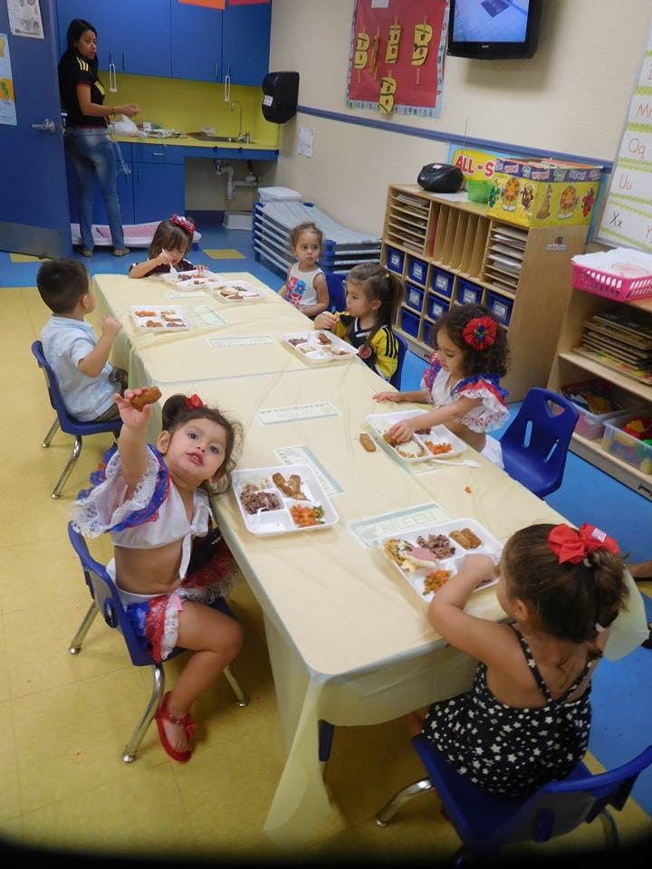 Children eating at a long table in a classroom