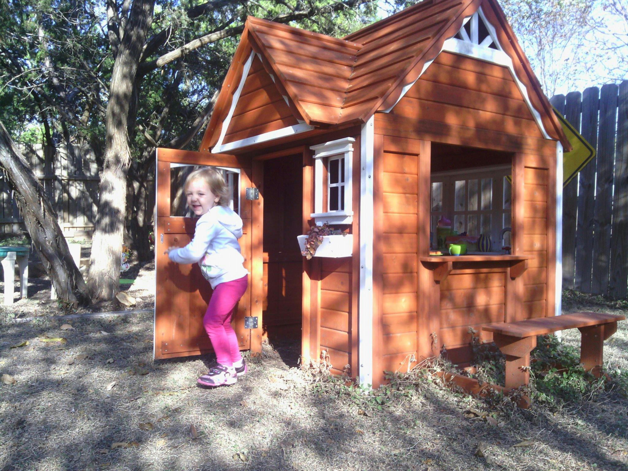 Child standing in the doorway of a wooden playhouse