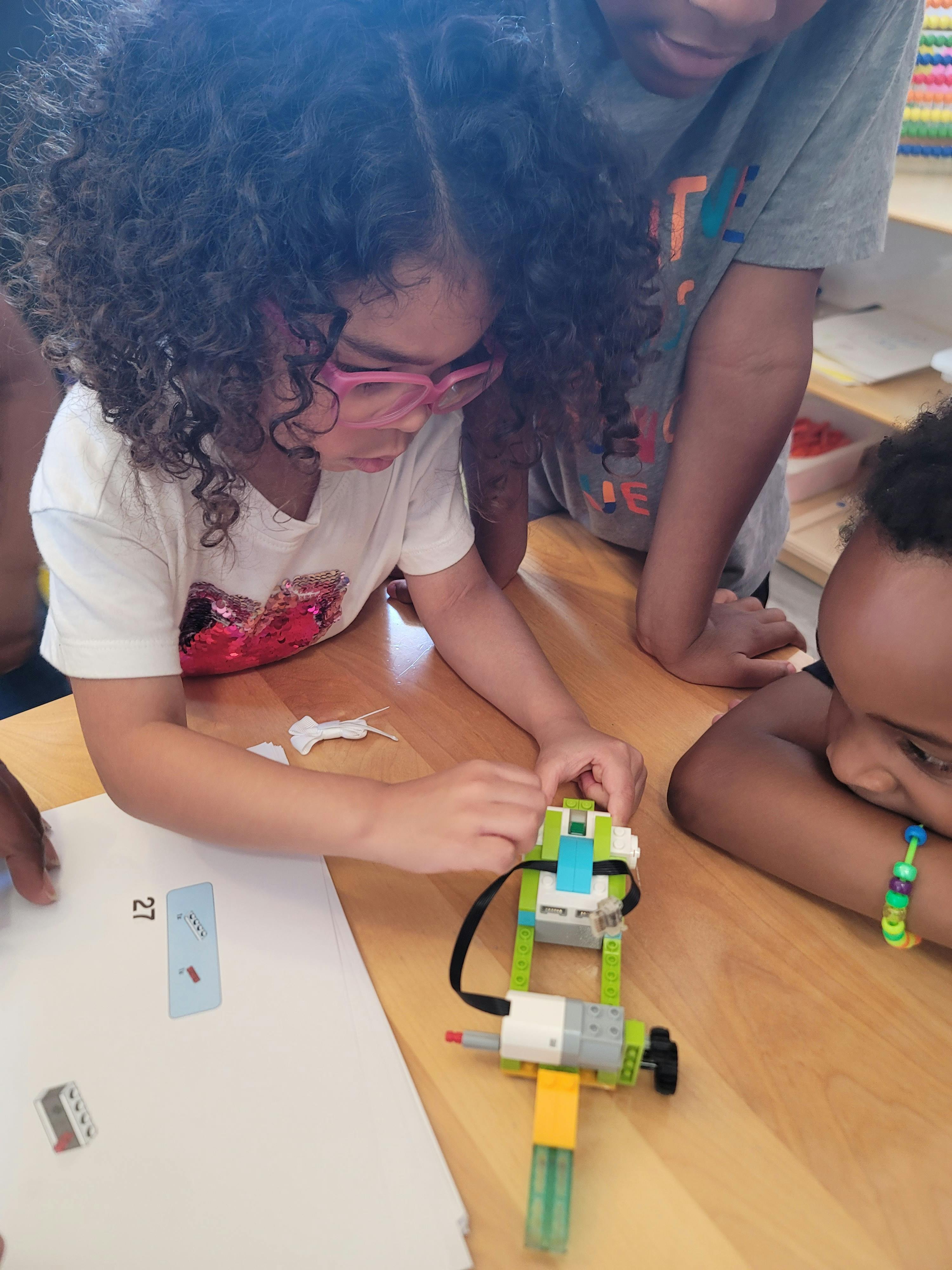 Child in pink glasses building with colorful blocks