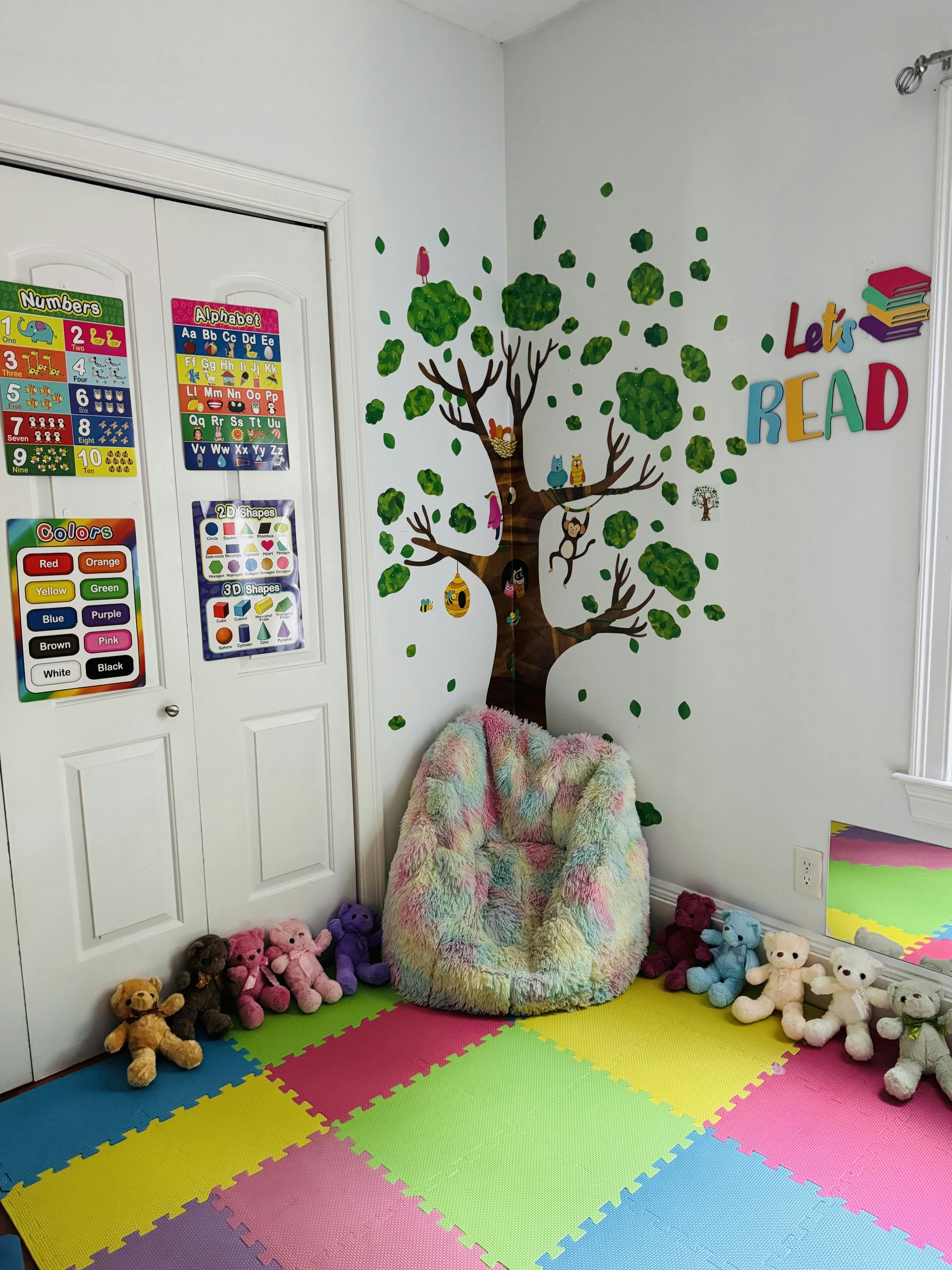 Reading nook with a tree wall decal, beanbag chair, and colorful floor mats