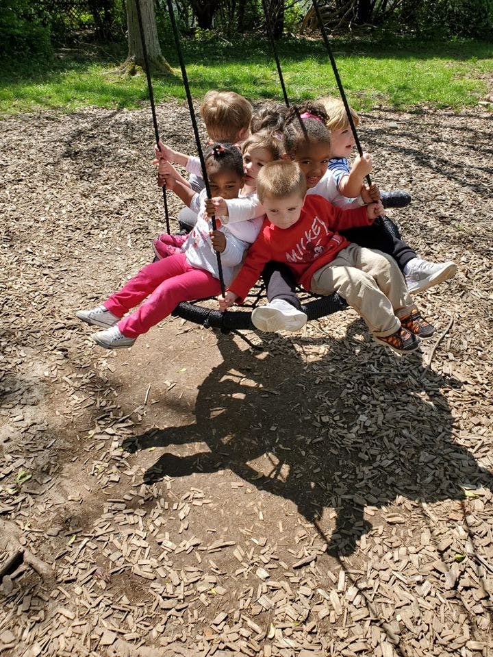 Multiple children sitting on a large swing