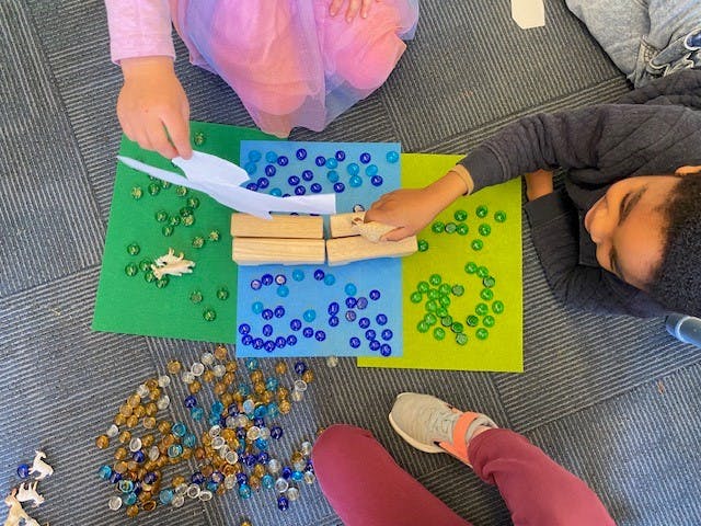 Two children playing with beads and wooden blocks on colorful mats