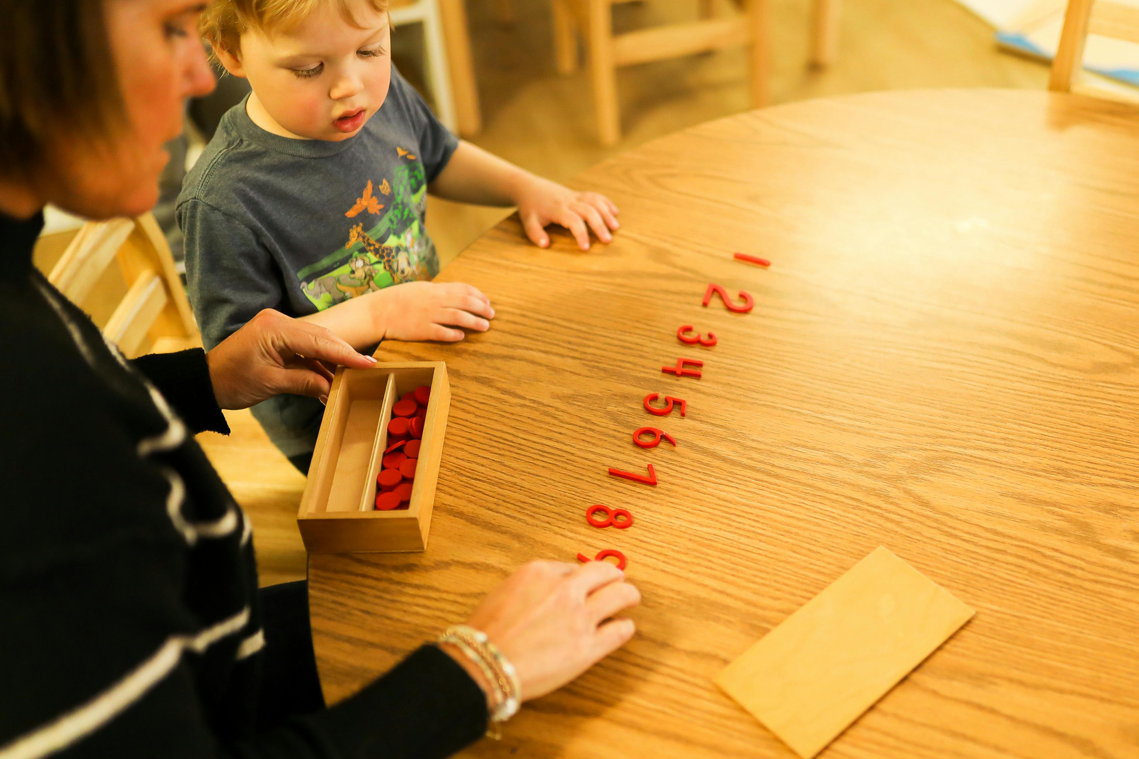 Person and child arranging number tiles on a table
