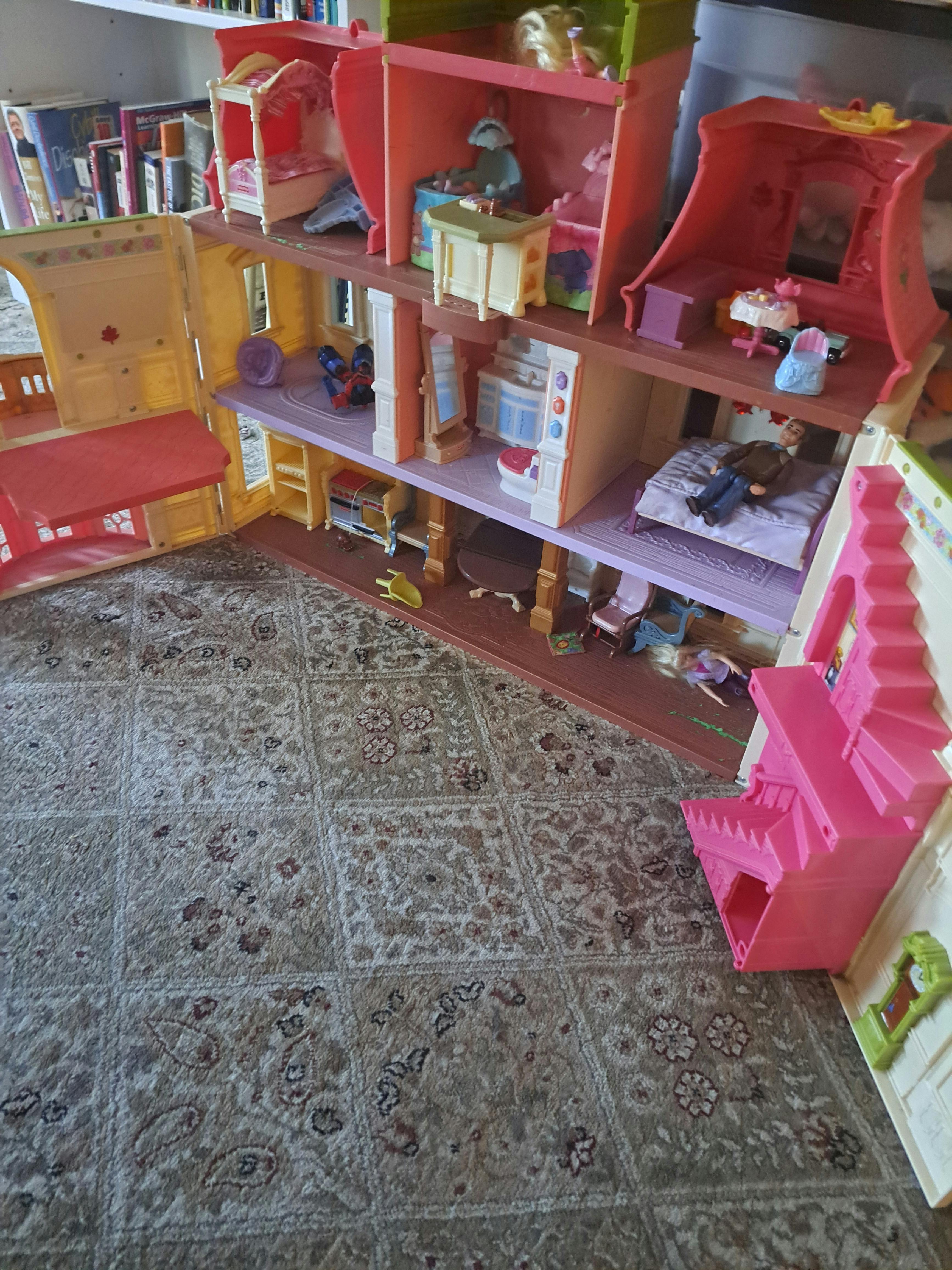 Large dollhouse with multiple rooms and furniture on a patterned rug