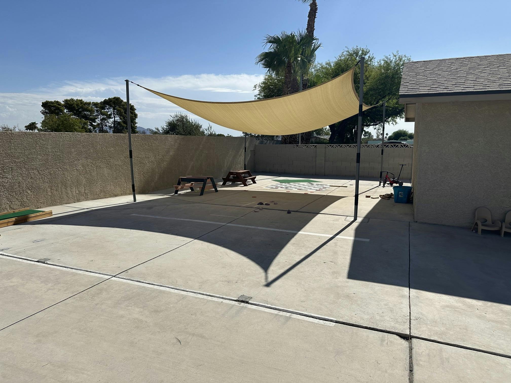 Backyard patio with a large shade sail covering tables and game area