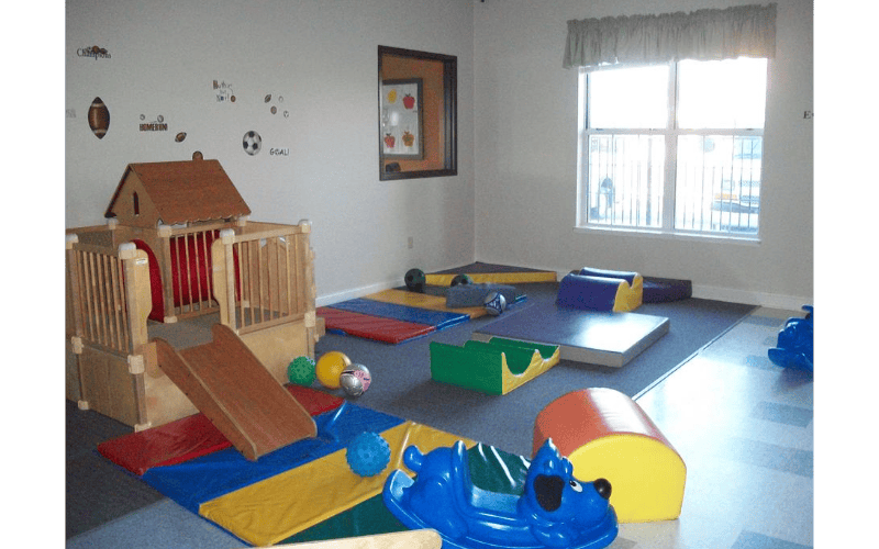 Indoor play area with wooden climbing structure and soft mats
