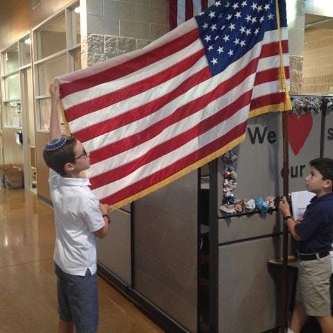 Two children holding an American flag indoors