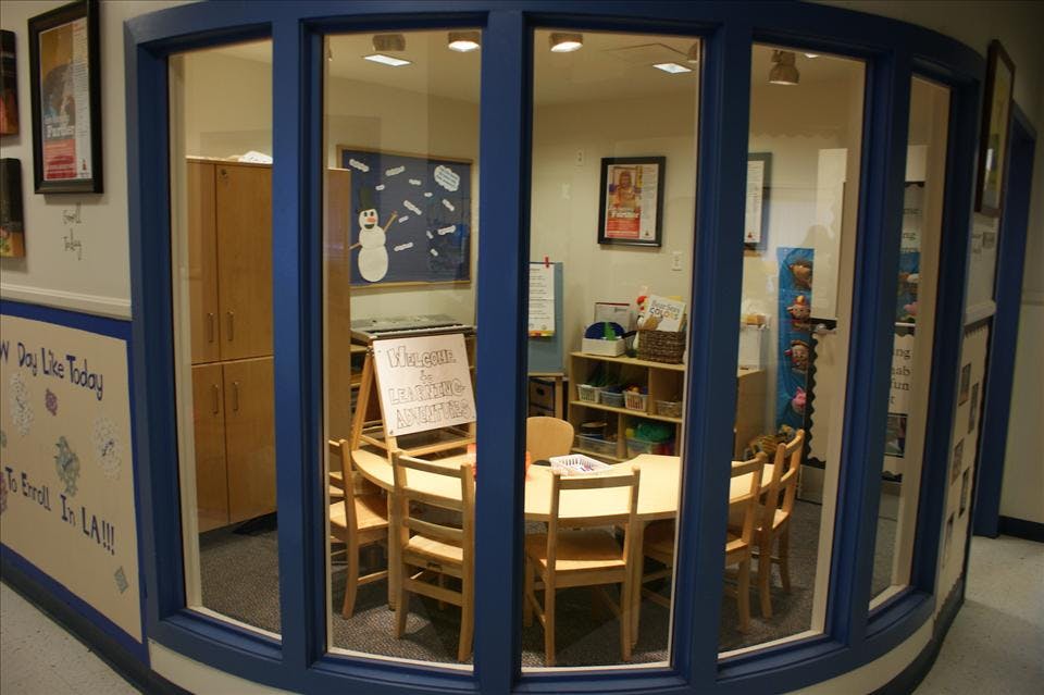 Classroom with a round table and small chairs, viewed through a curved window
