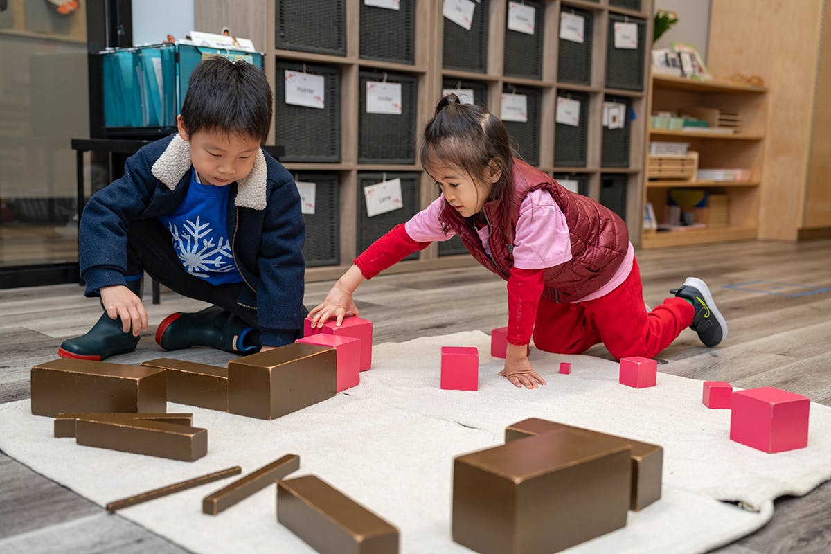 Two children playing with blocks on a rug in a classroom