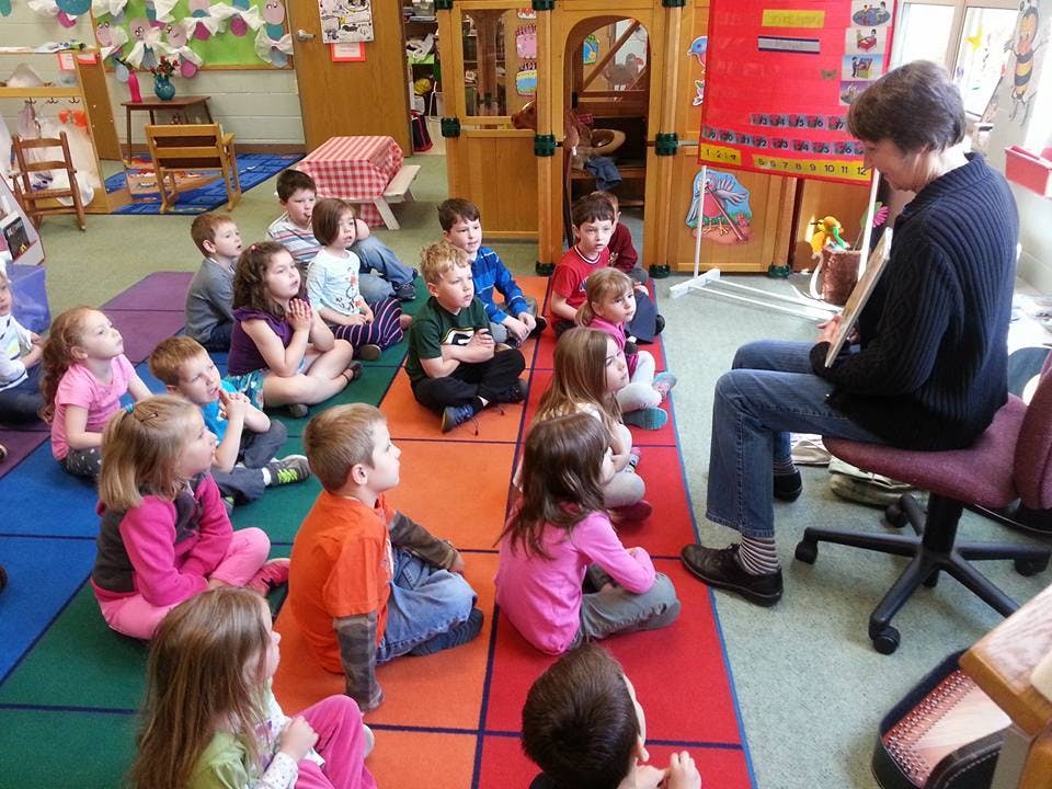 Adult reading to a group of children in a classroom