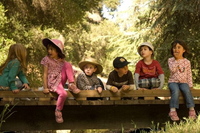 Five children sitting on a wooden structure outdoors