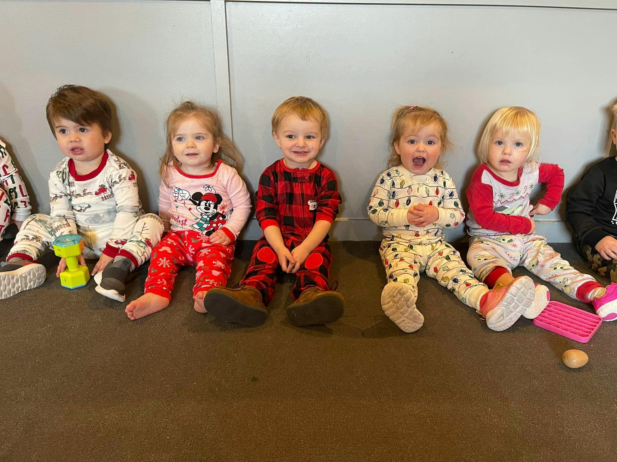 Five children sitting on the floor in pajamas
