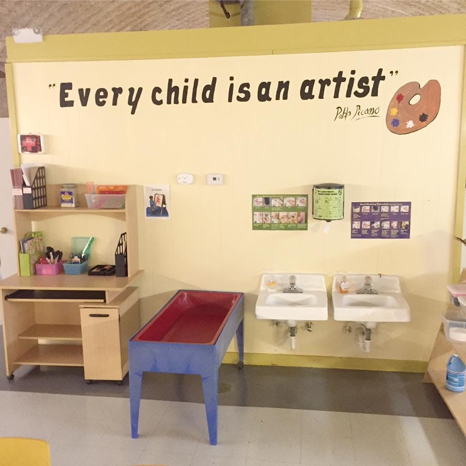 Classroom wall with quote "Every child is an artist" above two sinks