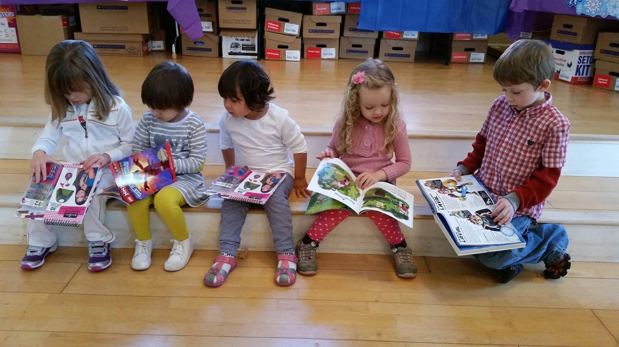 Five children sitting and reading books