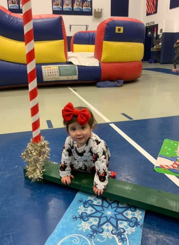 Child with a red bow crawling on a green beam